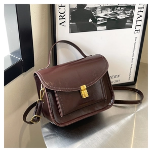 Détail d'un sac messager vintage en cuir rouge foncé avec boucle en métal doré chic