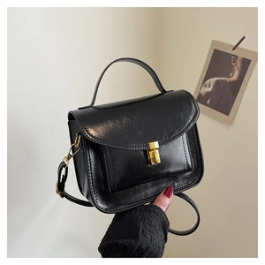 Détail d'un sac messager noir brillant avec fermoir doré et bandoulière réglable