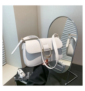 Detail view of white leather crossbody bag with polished gold U-shaped metal clasp