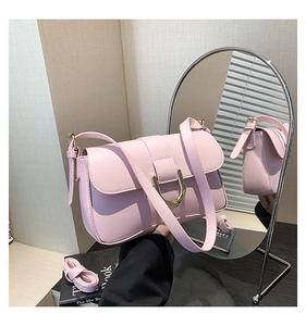 Detail view of pink leather handbag with gold D-buckle and mirror reflection