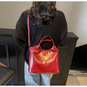 Close-up of a red glossy leather tote bag with a golden triangular logo for women