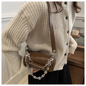 Detail view of dark brown cylinder bag with silver metal chain and fashion text strap
