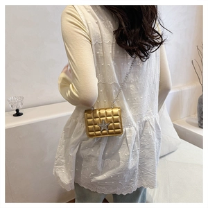 Detailed view of golden quilted crossbody bag with rhinestone star and silver chain strap