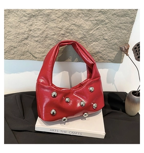 Detail of red glossy underarm bag with silver rivets placed on an art book