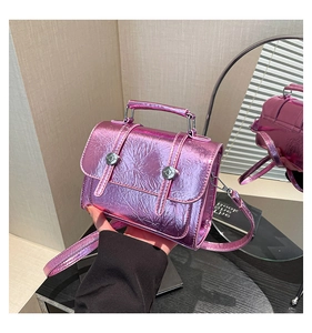 Macro view of metallic purple faux leather handbag with textured finish and metal buckles