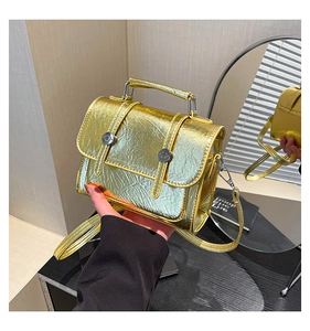 Detail of golden metallic crossbody bag featuring double buckles and wrinkled texture