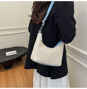 Detailed view of a woven shoulder bag with light blue trim worn by a model