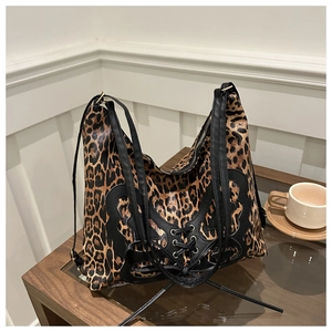 Detail of leopard print tote featuring black butterfly patchwork and lace-up accents