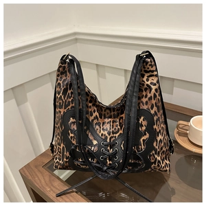 Detail of leopard print tote bag featuring black butterfly leather patch and lace-up design