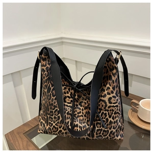 Vue détaillée du sac cabas léopard avec lanières en cuir noir sur table en bois