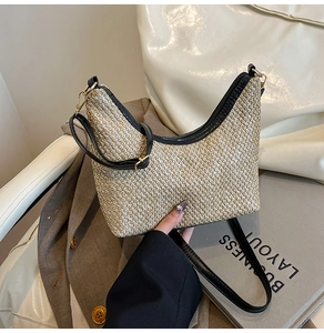 Close-up of crescent straw woven bag with black leather trim and metal zipper detail