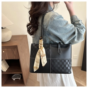 Detail of black patchwork tote bag with woven texture and decorative silk scarf