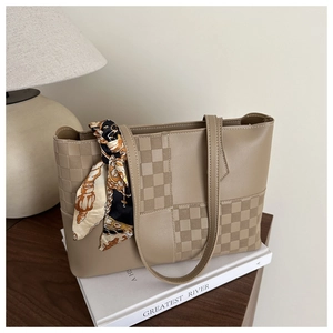 Detail of khaki tote bag with checkerboard pattern and silk scarf on books