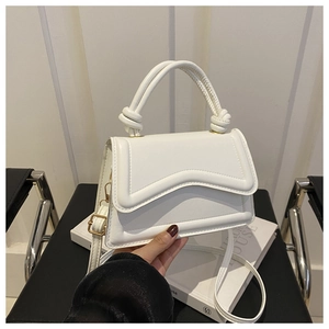 Close-up of white textured leather crossbody bag with wavy stitching and knot handle details