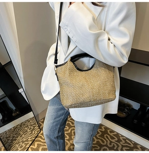 Detail of hand-woven straw tote with black trim and straps worn over the shoulder