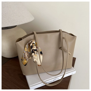Detail of a khaki tote bag with a decorative silk scarf on the handle and large capacity