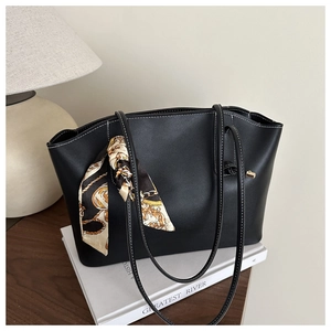 Detail of a black tote bag with white contrast stitching and an elegant silk scarf accent