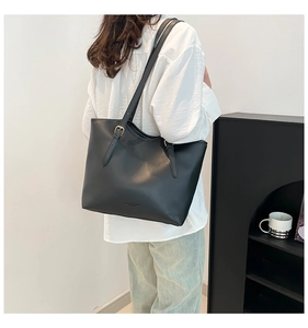 Detail of black tote bag with golden metal hardware buckle and smooth texture finish