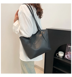 Close-up of the black leather tote bag with a metal adjustable strap buckle detail