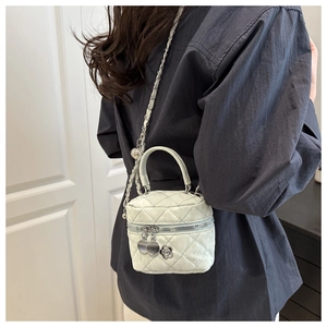 Détail d'un mini sac seau matelassé avec bandoulière chaîne et breloque fleur