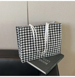 Detailed view of black and white houndstooth tote bag on a stylish office sofa
