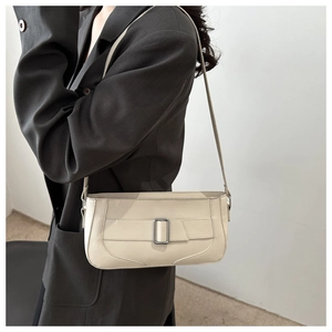 Detail of cream baguette underarm bag featuring a silver rectangular metal buckle clasp