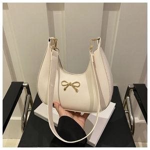 Detailed macro view of cream PU leather hobo bag with gold metal bow buckle and fine texture