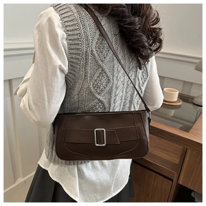 Detail of a dark brown shoulder bag with silver buckle worn during daily activities