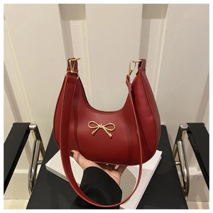 Detail of red hobo bag with matte leather finish and a golden bow metal ornament