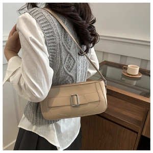 Chic beige leather baguette bag with silver buckle worn on shoulder in modern interior