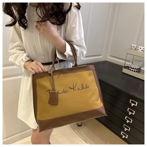 Detail of the vintage mustard yellow canvas tote bag with brown leather trim and handles