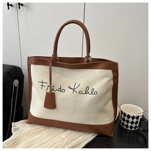 Detail of canvas tote bag with brown leather trim and Frida Kahlo artistic script