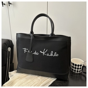 Detail view of large canvas tote bag with Frida Kahlo print and black leather trim