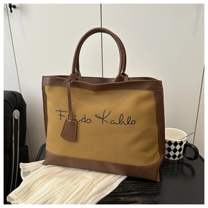 Detail of the Frida Kahlo script print on a yellow canvas tote bag with brown leather trim