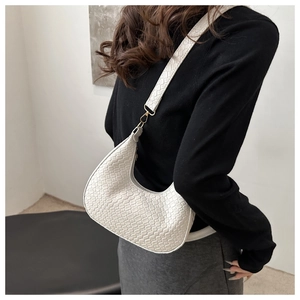 Detail of white woven crescent bag featuring fine texture and gold metal hardware