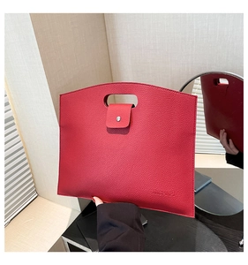 Detail of red litchi texture briefcase with top handle and embossed logo for office work