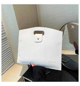 Detail of white lychee leather handbag featuring silver buckle and engraved lettering