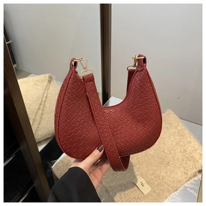 Detailed view of dark red crescent bag with crocodile texture and gold metal hooks