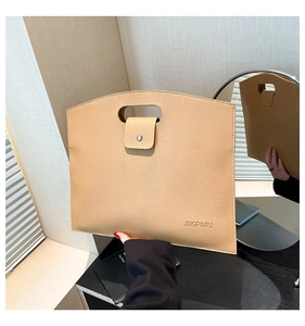 Detail of khaki lychee grain leather tote bag with cutout handle and metal buckle