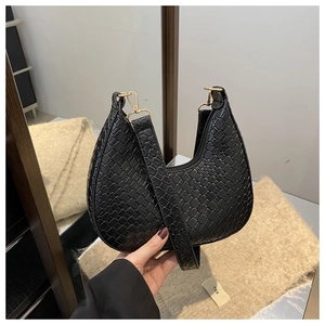 Detail of black crescent hobo bag featuring woven crocodile texture and gold hardware