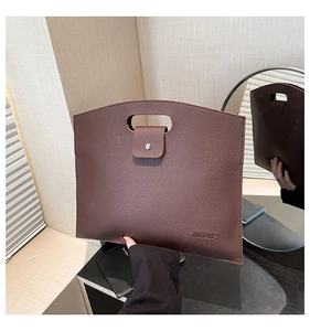 Close-up of deep brown lychee grain leather tote bag with handle and buckle