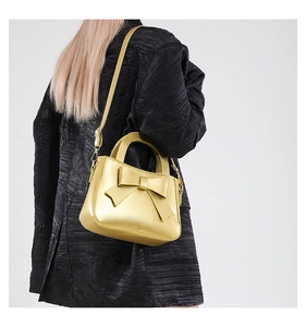 Borsa a mano metallica dorata alla moda con fiocco grande e tracolla sottile