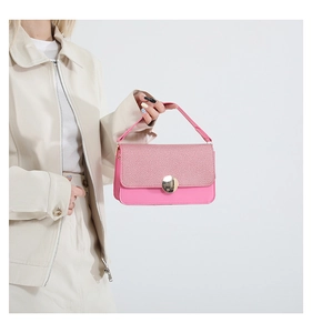 Detail view of pink crossbody bag featuring woven texture flap and gold circular buckle