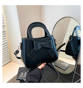 Dettaglio borsa elegante in pelle opaca nera con fiocco 3D e fibbia in metallo oro