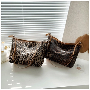 Dettaglio di borse tote leopardate chiare e scure con manici marroni su tavolo bianco