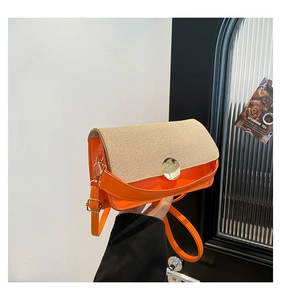 Detail of orange faux leather and beige woven fabric contrast on crossbody bag