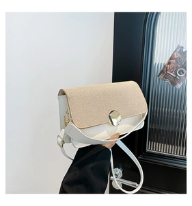 Close-up of white crossbody bag with beige woven flap and gold round buckle detail