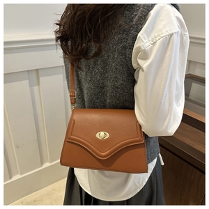 Close-up of brown leather bag featuring elegant V-quilted texture and gold rotary clasp