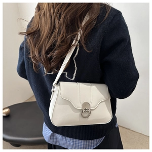 Vista posteriore di una donna con borsa a tracolla bianco crema e chiusura ad anello argento