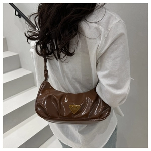 Detail of dark brown hobo bag with cloud pleats and a golden triangle metal emblem